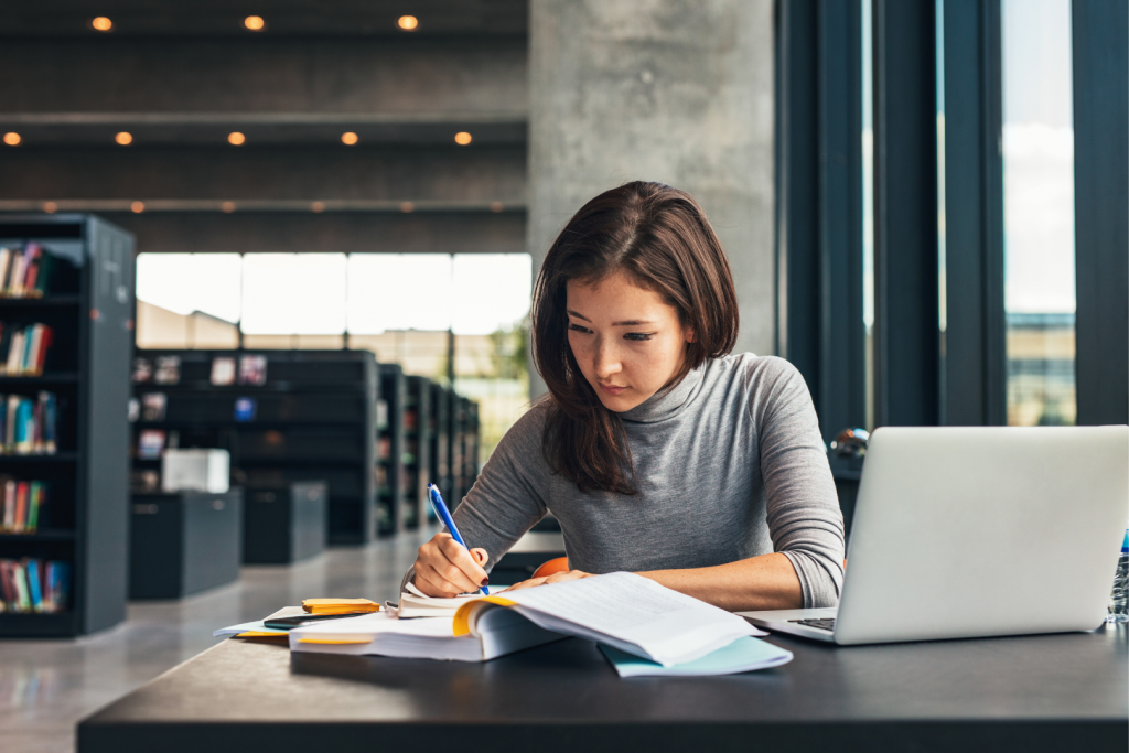 Woman writing research in library